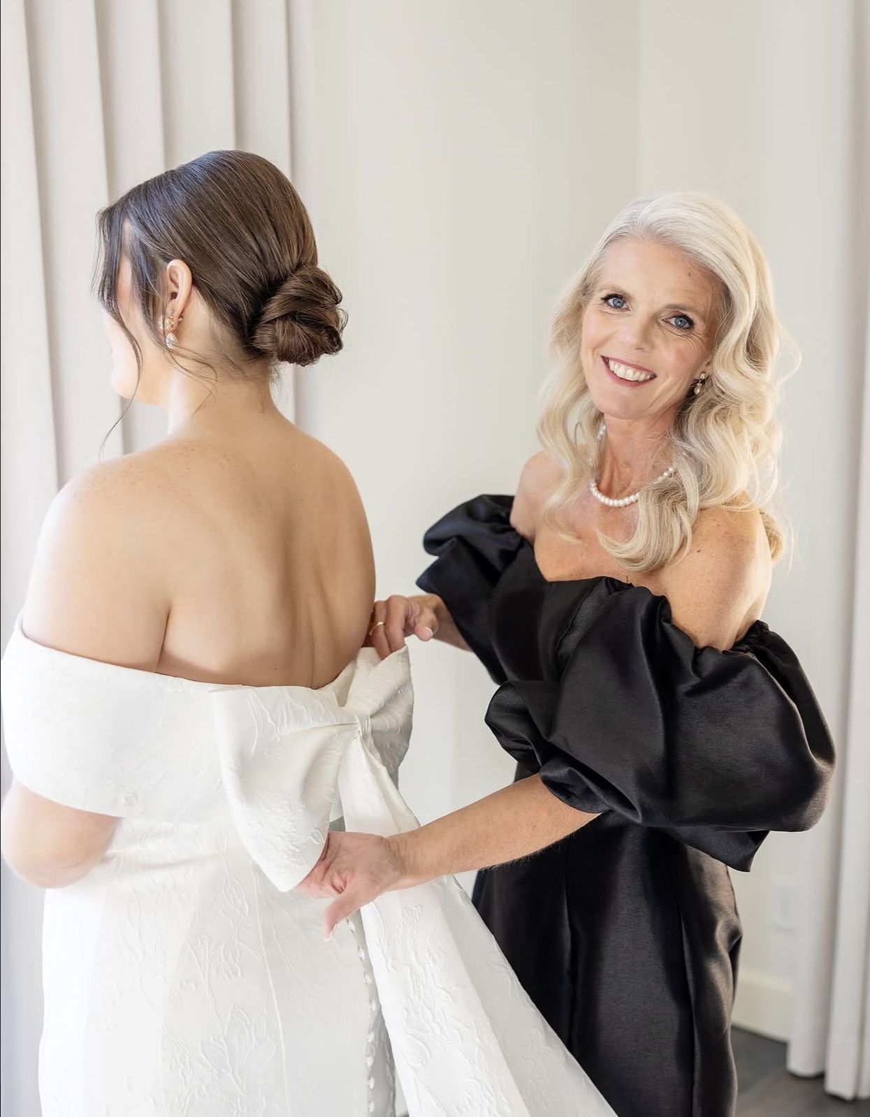 Bride being helped into her gown with a flawless Soleil bridal airbrush tan